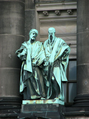 Bronzestatue von Matthäus und Markus am Berliner Dom. Zusammen mit Lukas bilden sie die Synoptiker unter den Evangelisten. Ihre Bibelstellen sind inhaltlich weitgehend gleich, unterscheiden sich aber im Stil, Botschaft & Theologie. Adr.: Am Lustgarten.