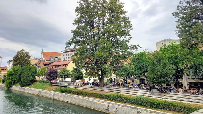 auf einer breiten Promenade reiht am Flussufer reiht sich ein Restaurant/Café ans andere