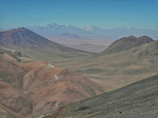 Schöne Sicht von hier oben. Der Vulkan ganz rechts mit etwas mehr Schnee ist der Llullaillaco, weit über 6000 m, und ca. 300 km weit weg. Der höchste chilenische Berg ist der Vulkan Ojos del Salado und ist weitere 200 km entfernt.