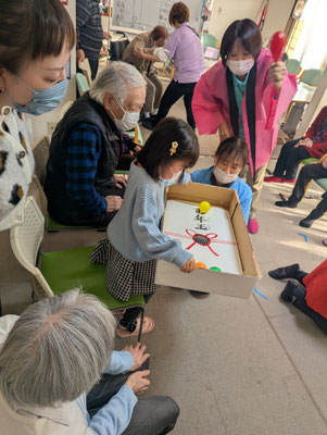 デイサービスの新年会でボールを落とすゲームを楽しむお子さん。