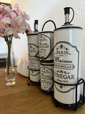 Stilvolle Küchendekoration in der Ferienwohnung „Auszeit Bergliebe“ mit eleganten Öl- und Essigspendern im Vintage-Design. Frische Blumen runden das Arrangement ab und verleihen der Küche eine charmante, persönliche Note.