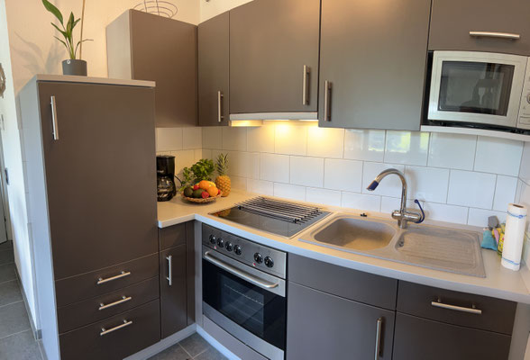 Moderne, voll ausgestattete Küche in der Ferienwohnung „Auszeit Bergliebe“ mit Ceranfeld, Backofen, Mikrowelle und stilvollen Fronten in warmem Braunton. Frisches Obst und eine Kaffeemaschine sorgen für zusätzlichen Komfort im Urlaub.