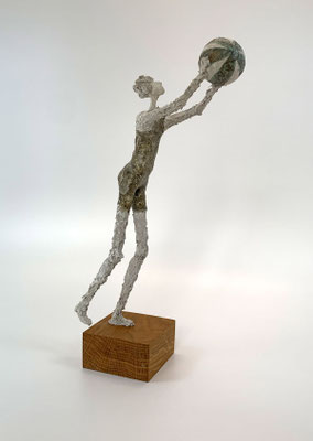 Monochrome Figur eines Badegastes mit Wasserball, gefertigt aus Papier-Komposit mit mineralischer Haptik.
