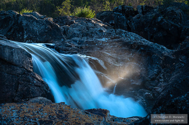 Das Abendlicht fällt auf die Gischt an einem Wasserfall im Abisko Nationalpark