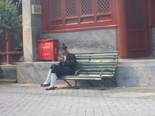 Moderne trifft Tradition: ein Mönch tippt eine SMS ins Handy (Peking 2005).