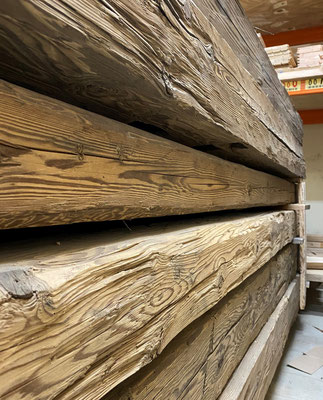 Detailaufnahme eines handgehackten Holzbalkens mit sichtbaren Werkzeugspuren