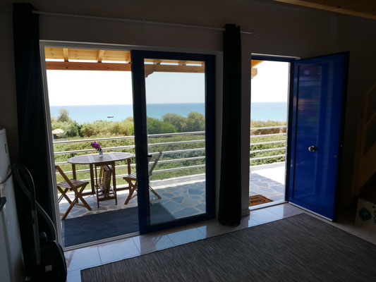 Blick durch die Panorama-Glasschiebetür auf die Veranda und das Meer