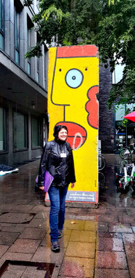 Le sourire même sous la pluie devant un morceau du mur de Berlin