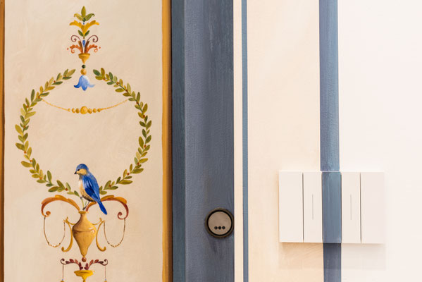 Decorazione di una porta ascensore con cornice, dettaglio interruttore luce