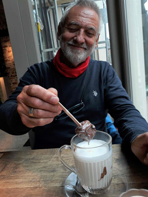 Die warme Schokolade wird serviert mit einem Glas heißer Milch, dazu ein großes Stück Schokolade am Spieß, die sich langsam auflöst, sehr lecker