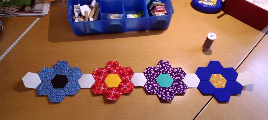 Dann werden die Blumen mit Zwischen-Hexagons in Reihen zusammen genäht. Danach werden die einzelnen Reihen zusammengenäht.