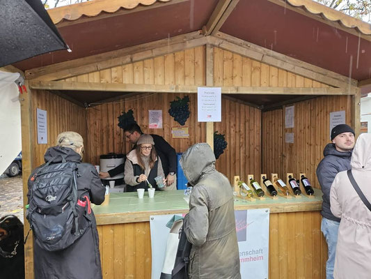 Zwei Erwachsene verkaufen an einem Marktstand Suppe und Wein