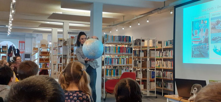 Die Autorin zeigt den Kindern etwas auf einem Globus