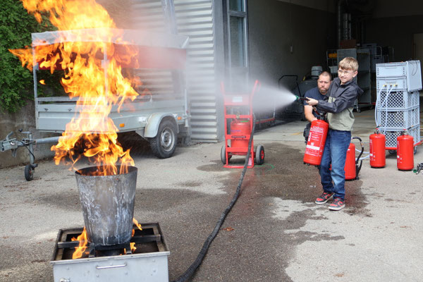 Ein Junge löscht mit Feuerlöscher