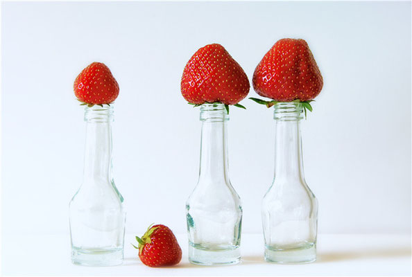 kleine Flaschen mit Erdbeer-Hüten