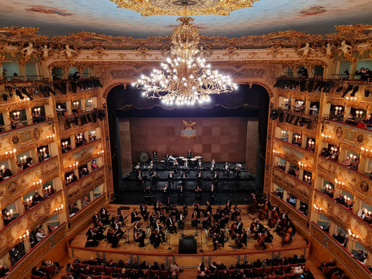 Deutliche räumliche Trennung von Streichern (Ebene über Orchestergraben) und Bläsern (Hauptbühne) wegen Corona. Dennoch tragen die Streicher Mund-Nasen-Schutz.