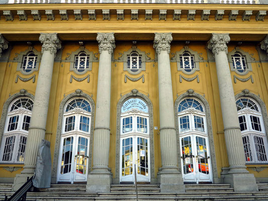 Széchenyi-Heilbad. Der von Säulen flankierte Haupteingang des Schwimmbades liegt gegenüber an der Állatkerti körút.