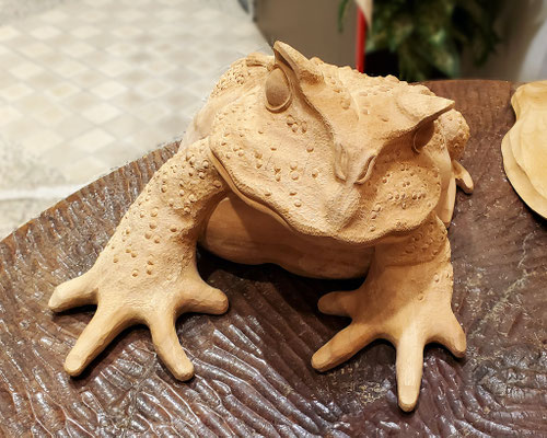 木彫りの技術でケヤキを使用して、カエルが両手をついていることから、人をお迎えする姿勢を表し、また無事に「帰る」との願いを込めて丁寧に彫り上げた縁起物の作品です。