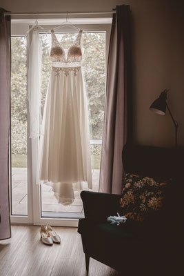 Brautkleid hängt vorm Fenster.