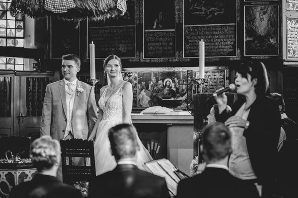 Brautpaar steht mit einer Sängerin vor dem Altar.