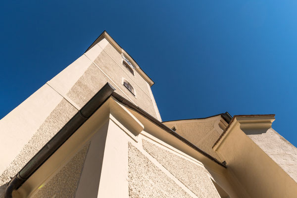 Der Turm der Pfarrkirche ragt in den blauen Himmel.