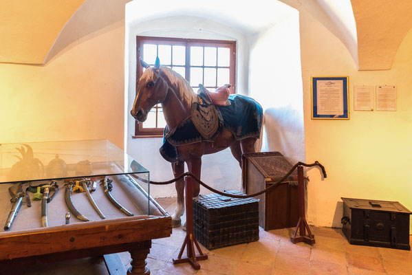 Pferd vor Vitrine mit verschiedenen Säbeln.