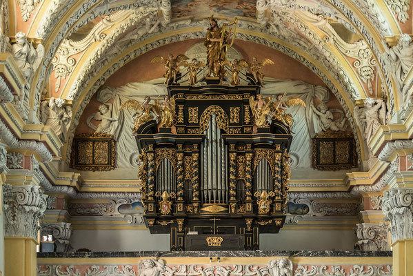 Die Orgel zeigt einen barocken Prospektaufbau mit drei Rundtürmen, bekrönt von einer Statue des harfespielenden David und Putti mit Instrumenten