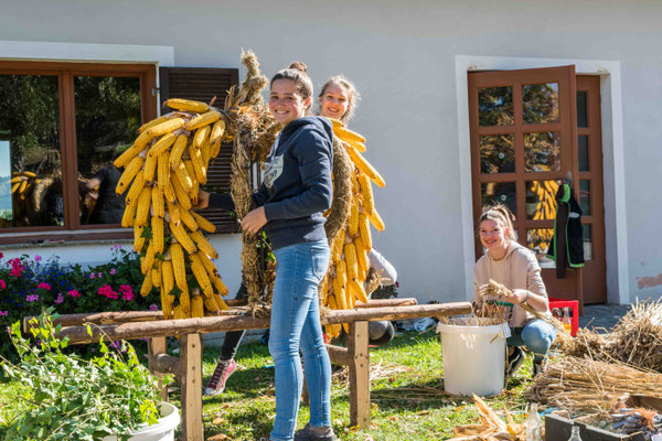 Mädls beim gestalten eines Erntedank Maiskranzes.