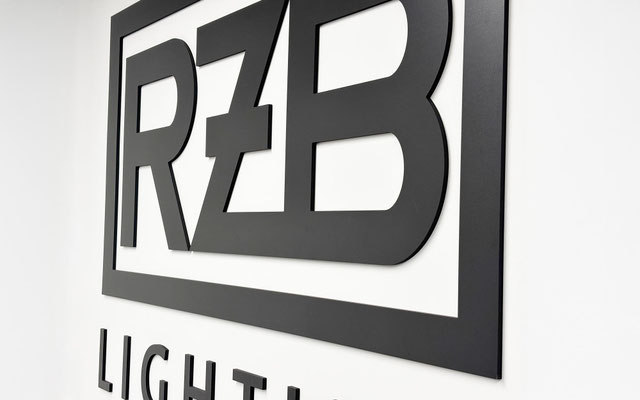 Große 3D-Wandbeschriftung des RZB-Logos aus gefrästem schwarzem Hartschaum im Showroom.