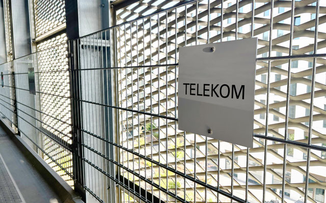Individuelle Stellplatzbeschilderung für die Telekom im Parkhaus – langlebige Schildermontage an Zaunelementen