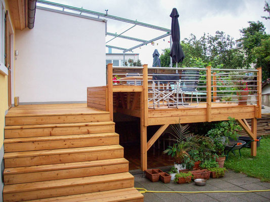 Terrasse mit Sitzgelegenheit aus Lärche mit Treppenaufgang und Geländer aus Edelstahl
