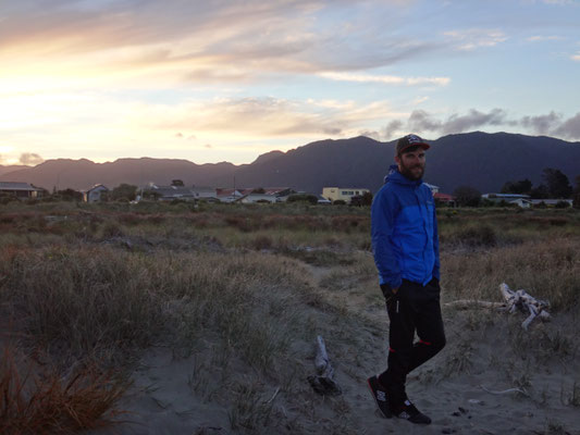 Am Strand im Sonnenuntergang mit dem Rücken zu Collingwood