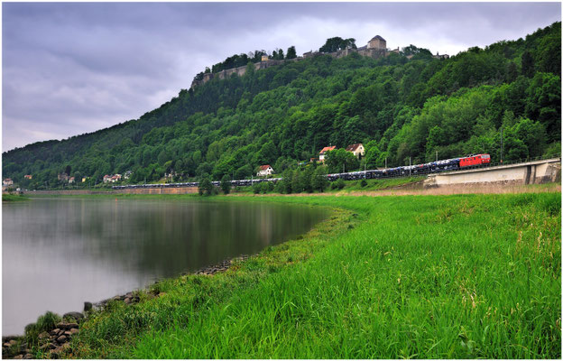 Eine BR 180 von DB Cargo legt sich mit ihrem Autozug unterhalb der imposanten Festung Königstein in die Kurve. Die Aufnahme ist ein Composing aus zwei Bildern, der Fluss wurde für die glatte Wasseroberfläche extra langzeitbelichtet. Mai 2012.
