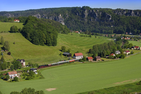 Blick vom Hörnelweg hinab ins Elbtal. Im Hintergrund das Basteimassiv und Rathen. Auf der Elbtalbahn ist ein Dampfzug unterwegs nach Tschechien. 