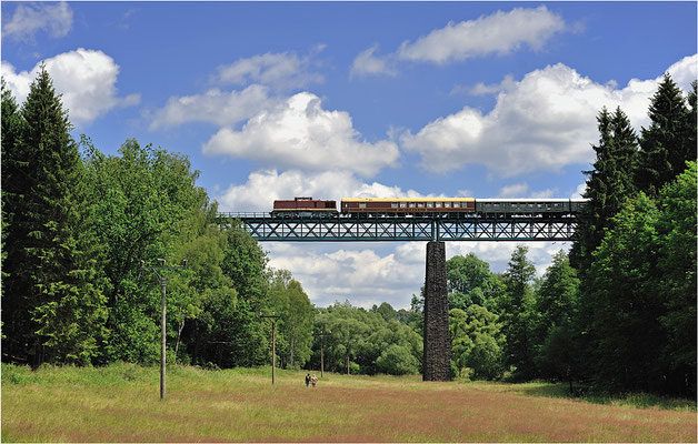 Zwei Wandersleute beobachten weit über ihren Köpfen den Sonderzug Sluknov-Sebnitz auf dem beeindruckenden Viadukt bei Vilémov.