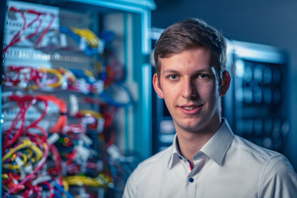 Ein IT-Mitarbeiter posiert für ein Portrait in einem Serverraum.  Corporate-Fotografie, Businessportrait Portrait 