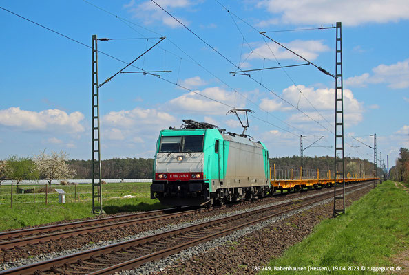 Bei schönstem Frühlingswetter zieht 186 249 am 19.04.2023 eine lange Leine Flachwagen durch Babenhausen.