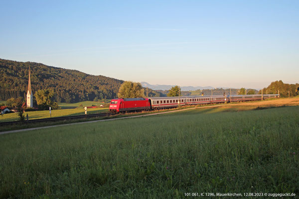 101 061 schiebt am 12. August 2023 bei Mauerkirchen kurz nach Sonnenaufgang den IC 1296 nach Frankfurt. Nächster Halt ist in wenigen Augenblicken Bad Endorf.