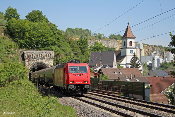 Die 185 586 "Heizprofi" der Rheincargo mit freundlich winkendem Lokführer lässt die Kirche in Istein am 07. Mai 2018 links liegen.