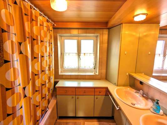 Das Badezimmer im charmanten Retro-Stil verfügt über zwei Waschbecken, eine Badewanne, Handtücher, Duschgel und Shampoo.
