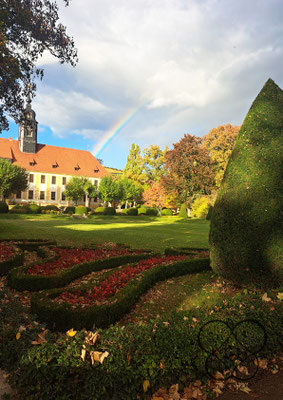 Foto vom Barockschloss Seußlitz, Perspektive vom Eingang Schlossgarten gesehen, mit spektakulärem Regenbogen
