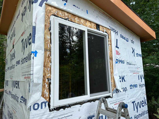 July 25, 2025. First window installed with proper flashing in progress.