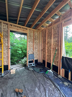 May 25, 2025. Completed OSB sheathing of third wall. Note rain tarps on roof and floor.