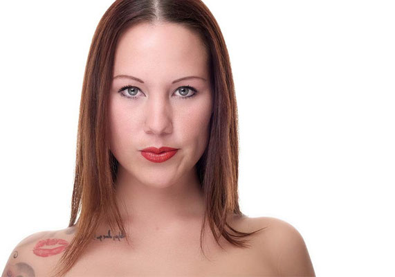 Professionelles Porträt einer Frau mit rotem Lippenstift, aufgenommen vor einem weißen Hintergrund in einem Fotostudio.