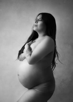 Strong maternity portrait of a woman embracing her body