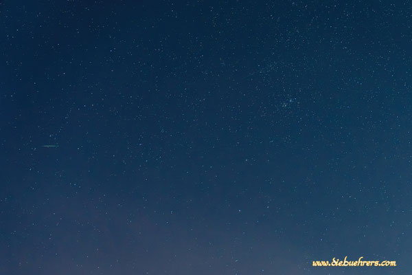 Mittig links eine kleine Sternschnuppe, oben rechts ist ganz schwach ein Starlink Satellit