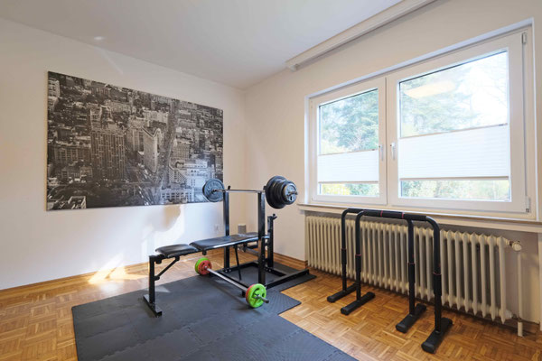 Zimmer mit Sportgeräten als Freizeitraum mit Fenstern zum Garten