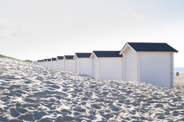 Eine Reihe weißer, kleiner Hütten am Strand in Südholland