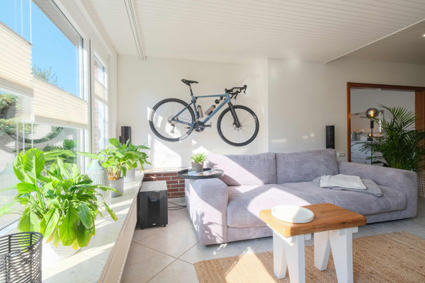 Modernes Wohnzimmer mit heller Einrichtung und Fahrrad an der Wand
