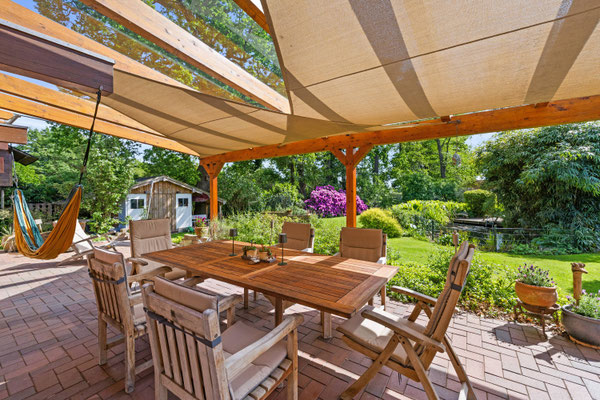 Terrasse mit langem Tisch und Stühlen zum Garten hin